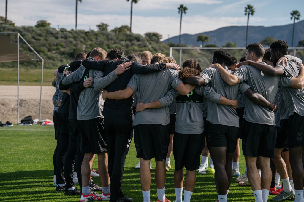 Team players gather in a huddle during preseason